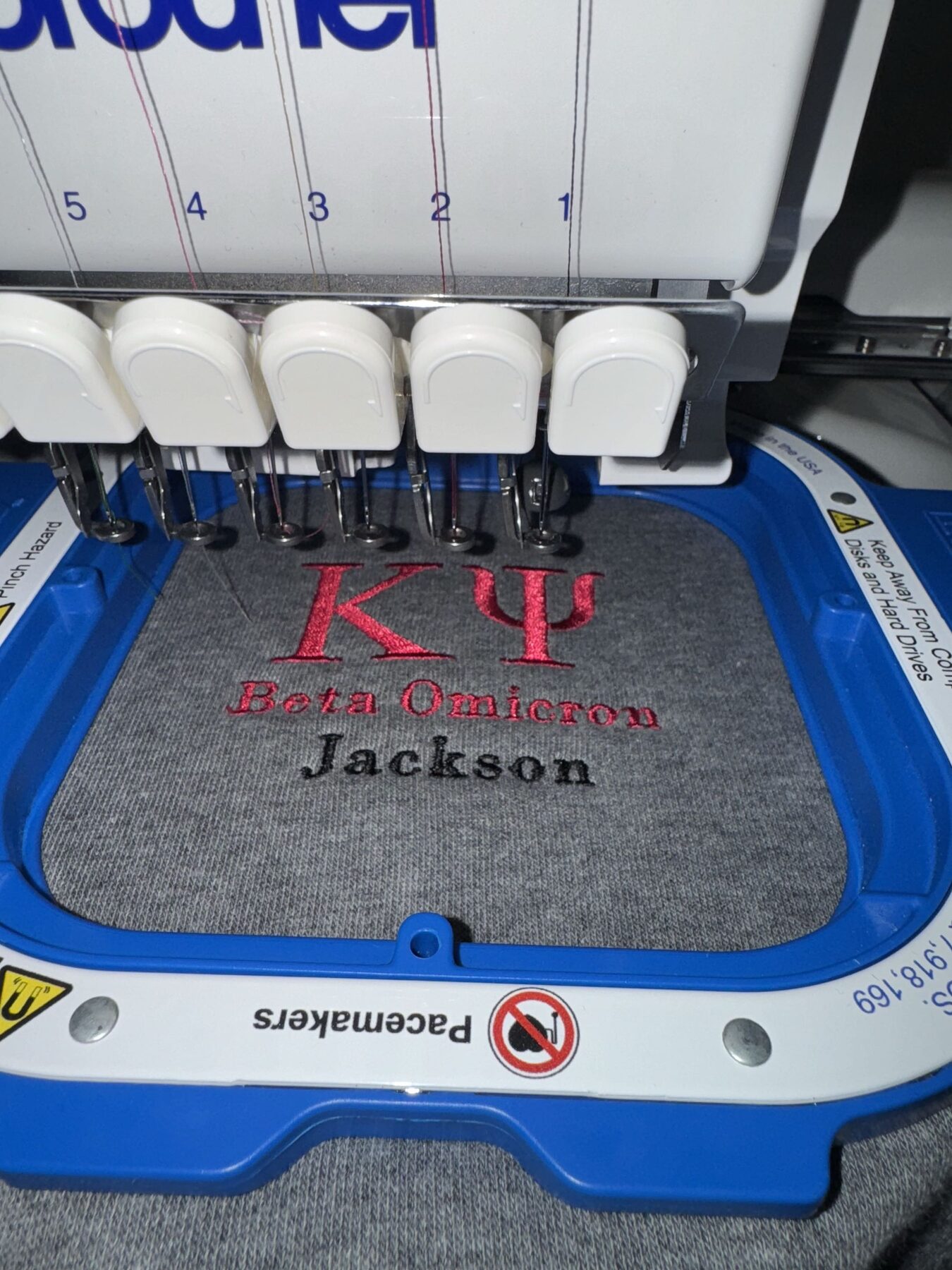 Embroidery machine stitching a Kappa Psi Greek-letter design