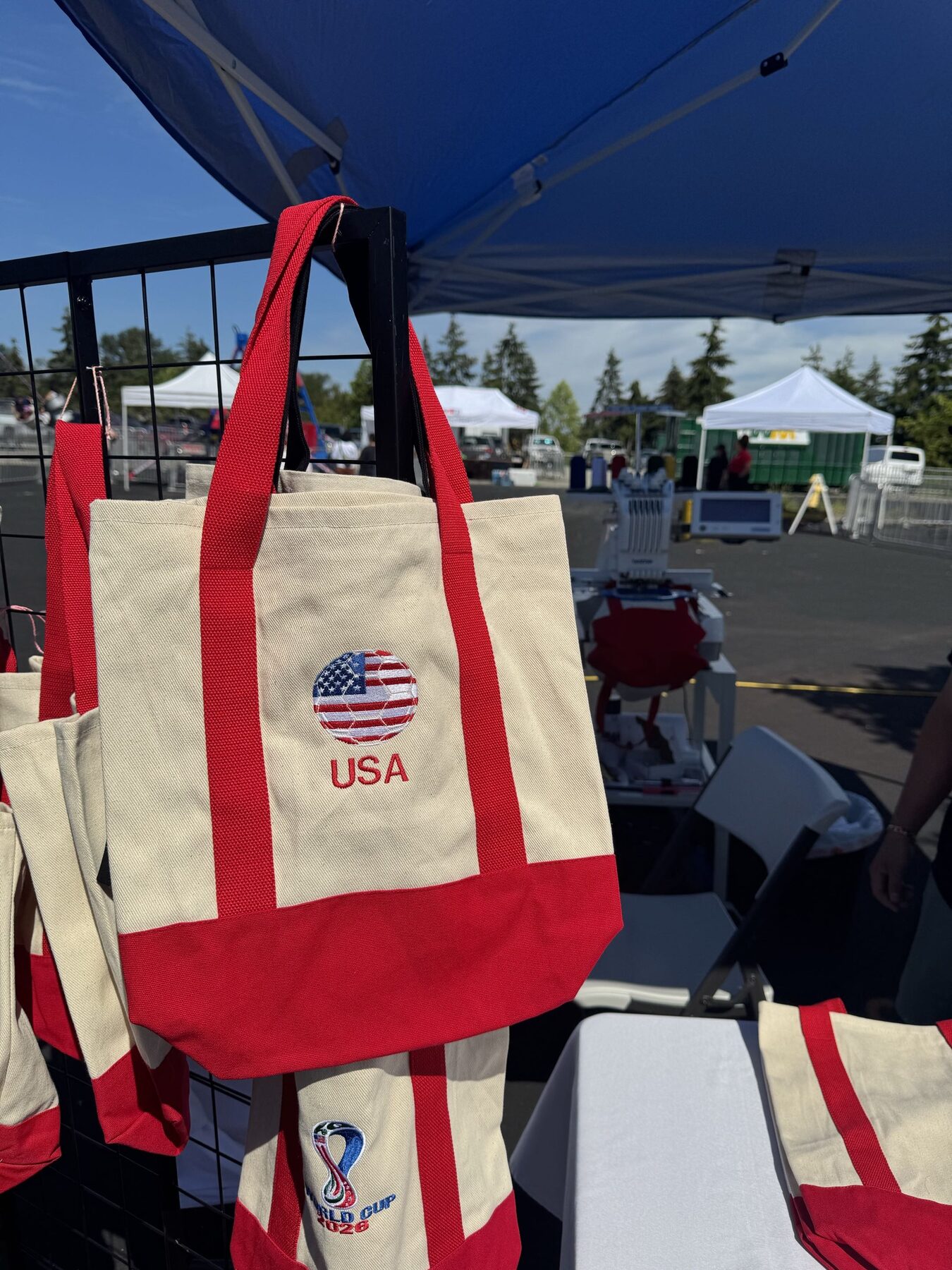Embroidered USA World Cup totes hanging at a Threadify market booth
